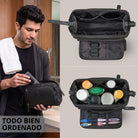 Neceser Henry de piel negro con amplia apertura, varios compartimentos interiores, bolsillo de malla y asa, hombre guardando productos