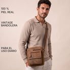 Bandolera plana de hombre en piel marrón, llevada cruzada sobre el torso, con bolsillos frontales y correa ajustable.