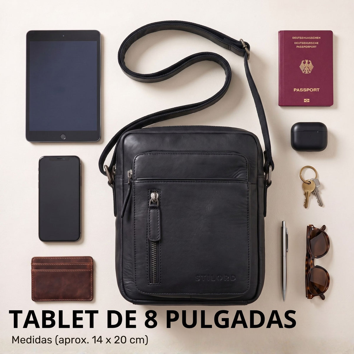 Kleine schwarze Leder-Umhängetasche, Frontansicht mit Trageriemen, daneben 8-Zoll-Tablet, Reisepass, Handy, Geldbörse und Schlüssel
